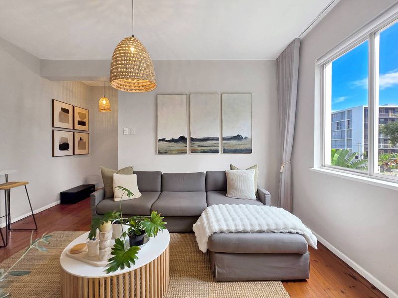 A bright and inviting living room featuring warm timber flooring and a large window that allows for ample natural light.