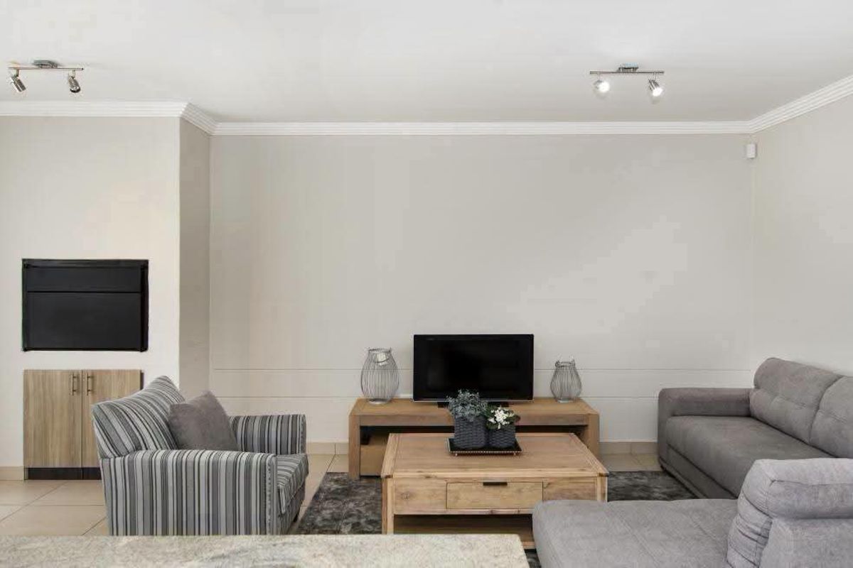 A well-maintained living room featuring a built-in fireplace, custom cabinetry, crown molding, and modern track lighting.
