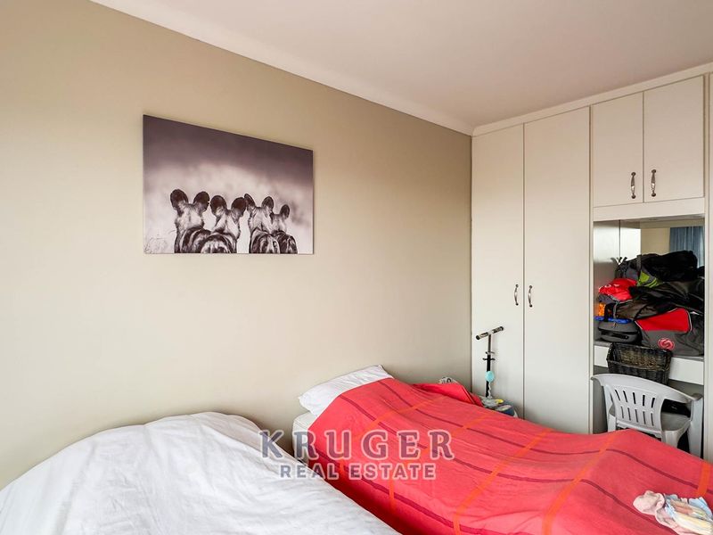 A bedroom featuring neutral wall tones and integrated built-in cupboards with a dedicated vanity section.