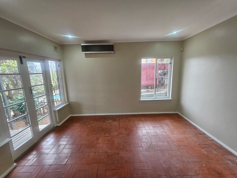 An empty living room featuring terracotta tile flooring, an air conditioning unit, and french doors leading to the exterior.