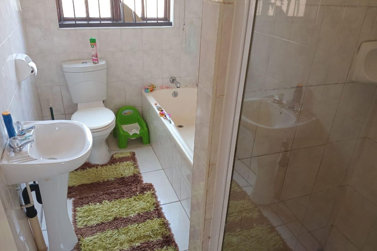 A functional bathroom featuring a pedestal basin, toilet, bathtub, and a separate shower enclosure with tiled walls and flooring.