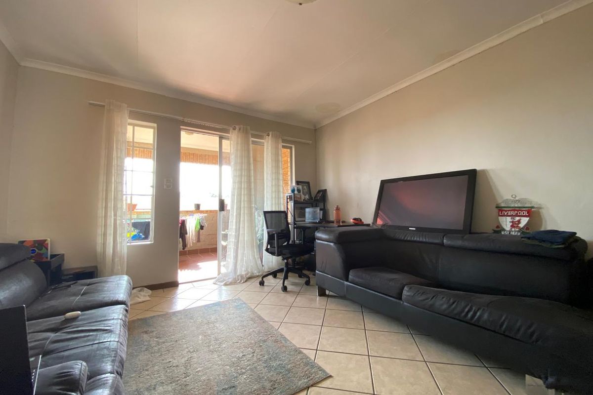 A living room featuring tiled flooring and sliding glass doors that provide access to an outdoor balcony area.