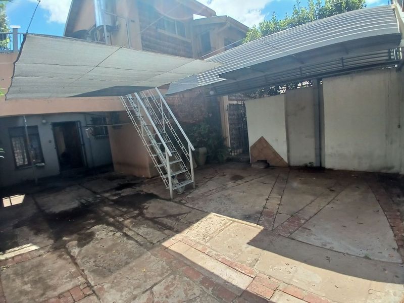 Rear courtyard area featuring a metal staircase, shade sail, and paved flooring, providing functional outdoor space with potential for improvement.