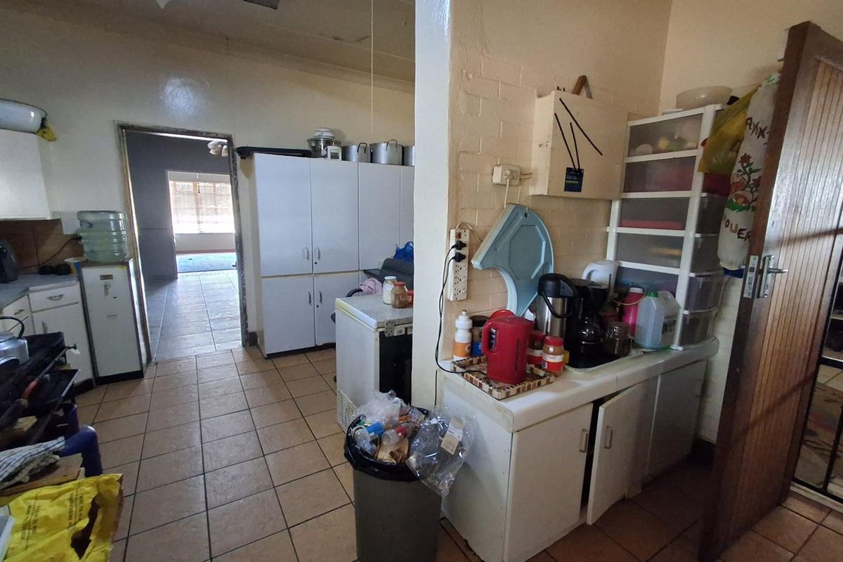 A functional kitchen area featuring tiled flooring and built-in cabinetry, offering potential for modernization and layout optimization.