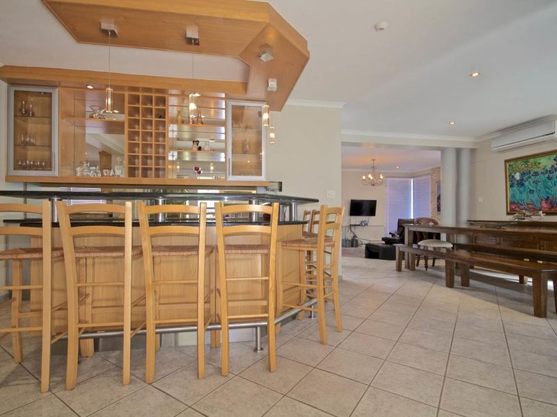 A well-appointed home bar area featuring a custom wooden bar counter with granite top, integrated wine storage, and tiled flooring, flowing into the living space.