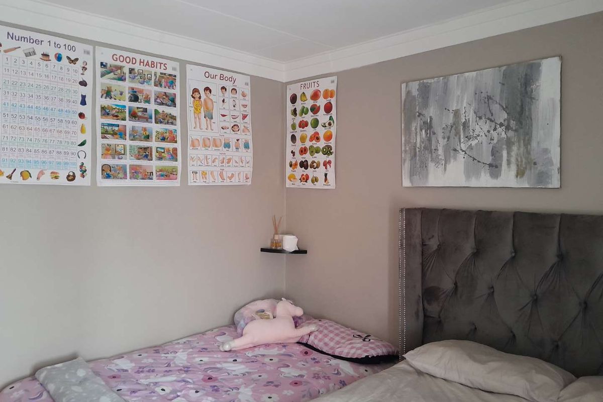 A bedroom featuring neutral wall tones, crown molding, and a tufted headboard, providing a comfortable and well-maintained sleeping space.