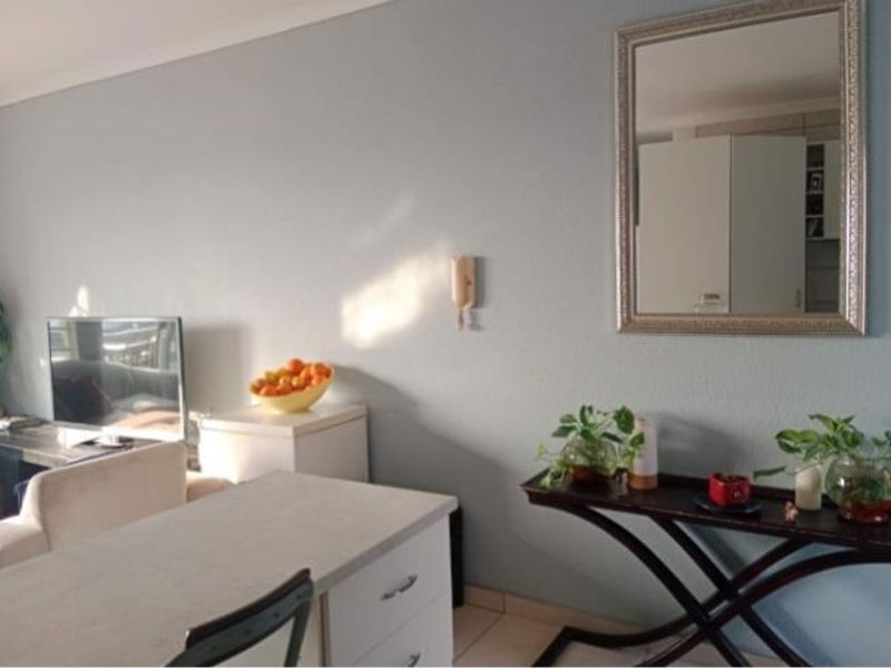 A living area featuring neutral wall tones, tiled flooring, and a wall-mounted intercom system, providing a functional and well-lit space.