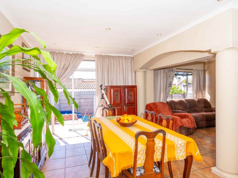 Open-plan living and dining area featuring tiled flooring, an architectural archway with a decorative column, and direct access to the outdoor patio area.