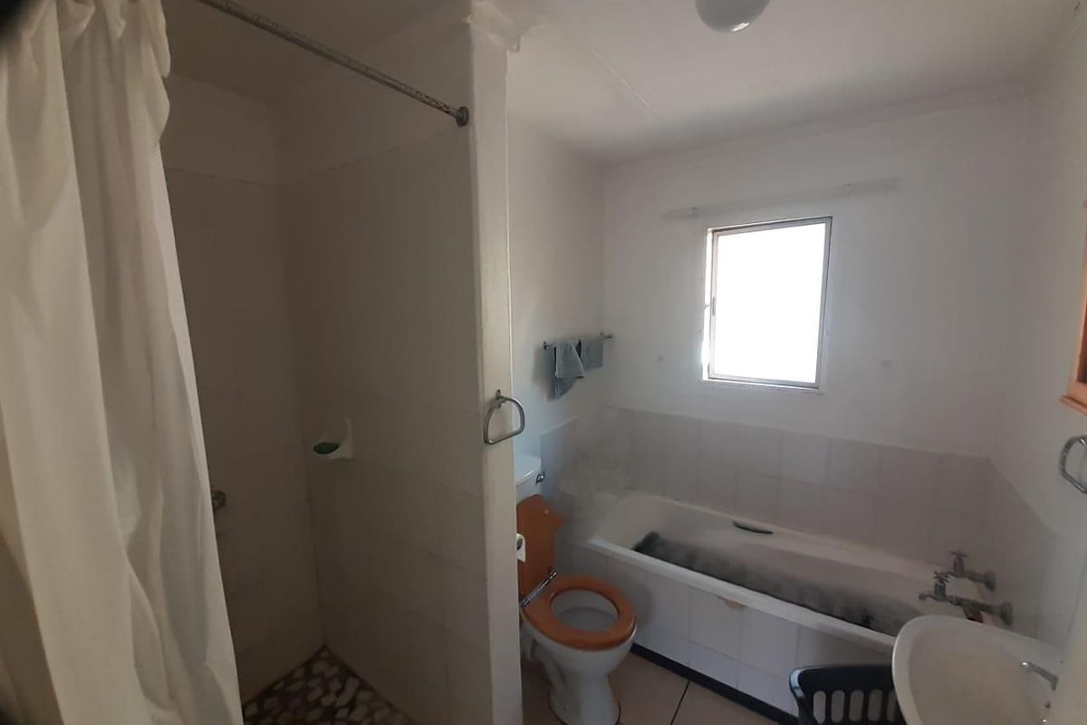 A dated bathroom featuring a separate shower, bathtub, toilet, and basin, requiring modernization and repairs to finishes.