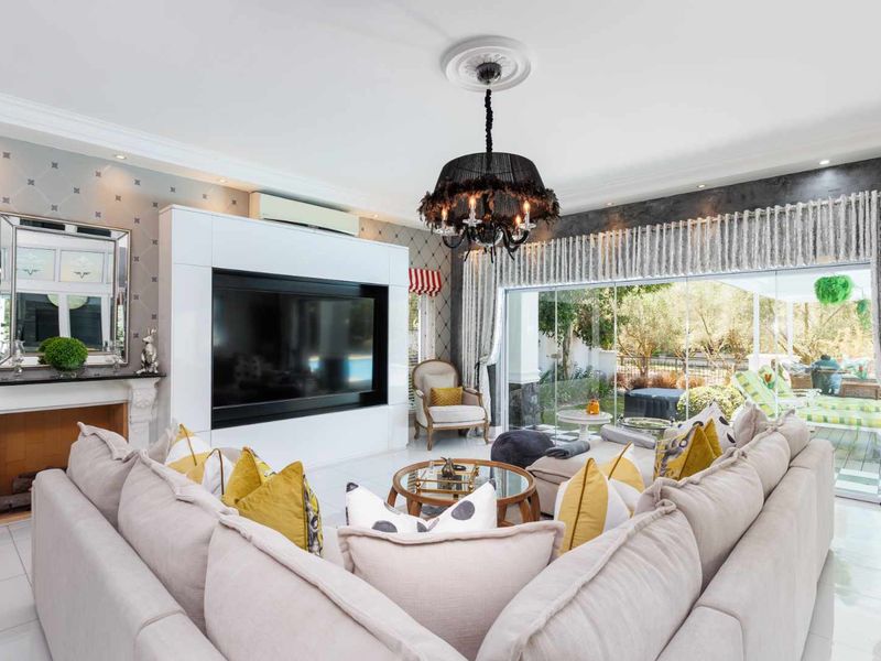 Spacious living room featuring a built-in fireplace, custom media cabinetry, split-system air conditioning, and large sliding glass doors opening to the garden.