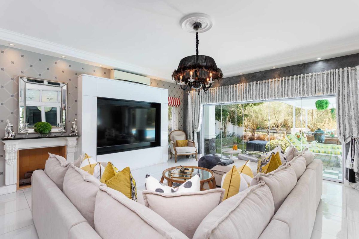 Spacious living room featuring a built-in fireplace, custom media cabinetry, split-system air conditioning, and large sliding glass doors opening to the garden.