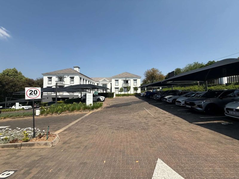 Front view of a professional office complex featuring a paved driveway, ample covered parking, and well-maintained building facades.
