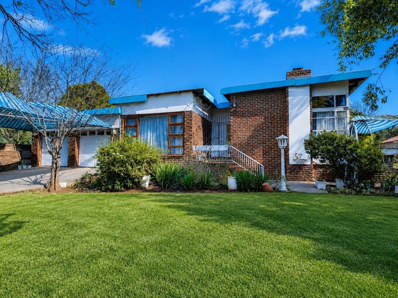 Front elevation of a brick house featuring a double garage, attached carport, and a well-maintained front lawn.