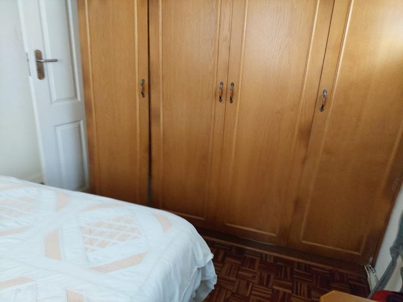 A bedroom featuring classic built-in wooden wardrobes and traditional parquet flooring, offering ample storage space.