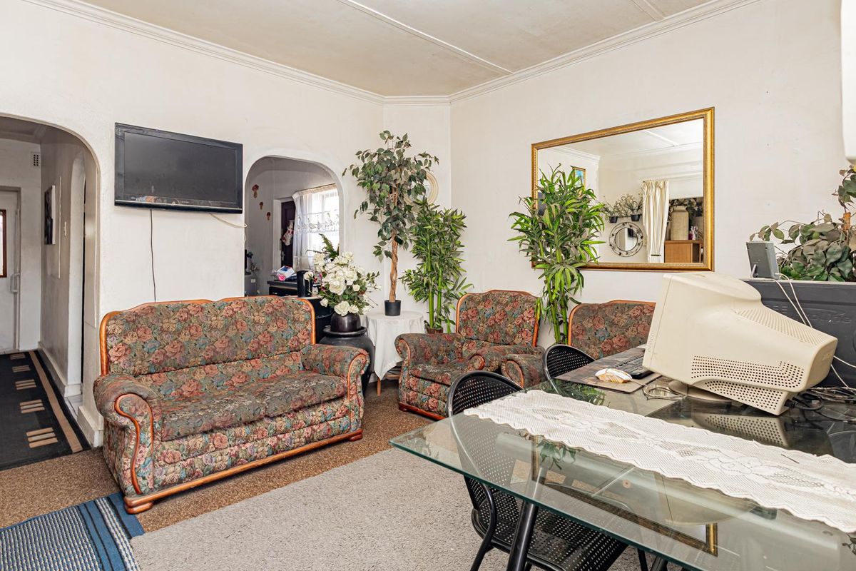 A living room featuring an arched entryway, coved ceilings, and carpeted flooring, offering a functional space with potential for modernization.