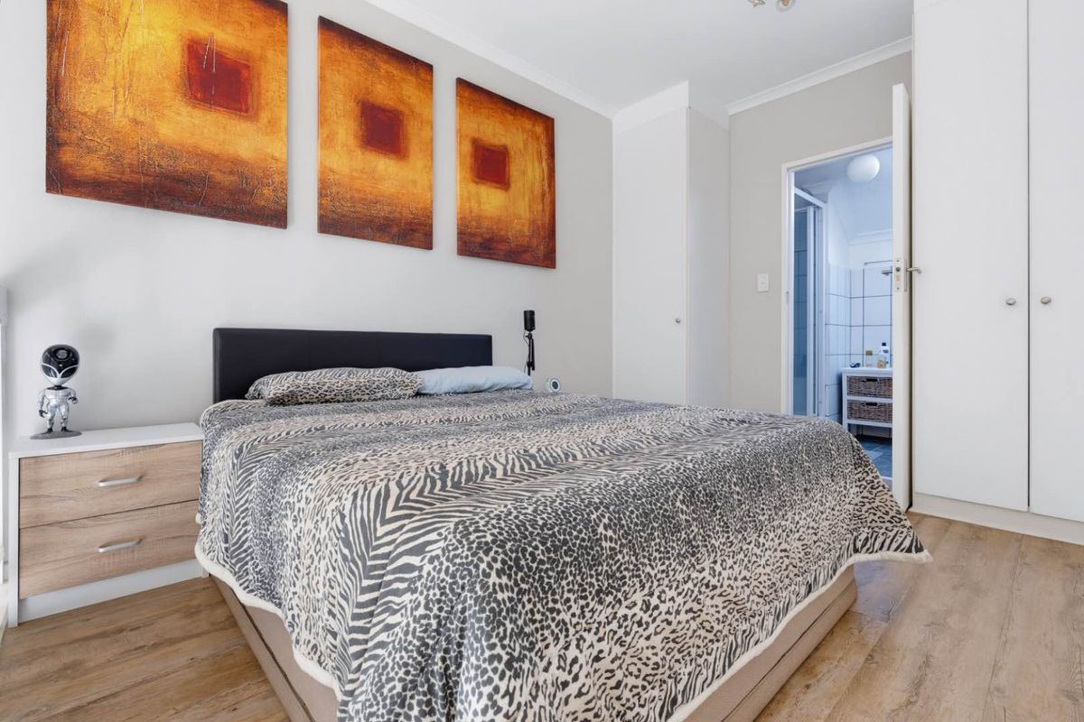 A well-maintained bedroom featuring laminate flooring, built-in cupboards, and direct access to an en-suite bathroom.