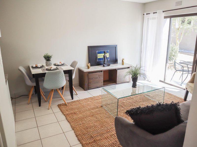 An open-plan living and dining area featuring neutral walls, ceramic floor tiles, and a sliding glass door providing access to the outdoor space.
