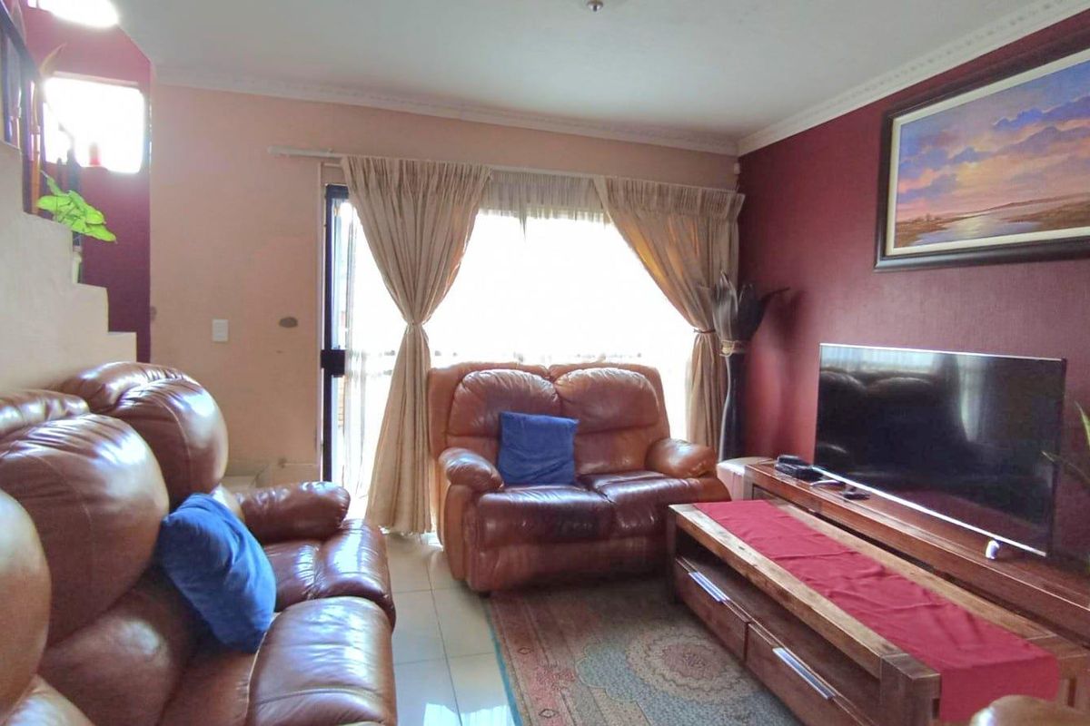 A living room featuring tiled flooring, a staircase, and a sliding glass door providing access to the exterior.