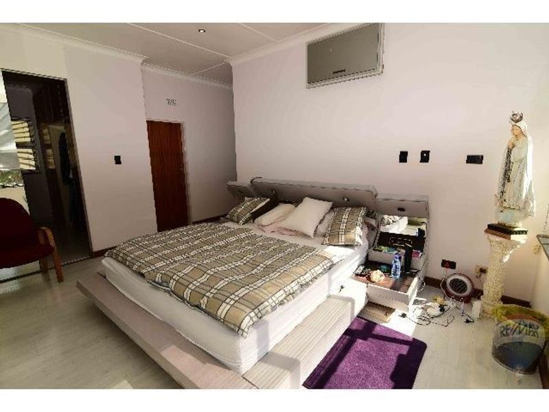 Spacious bedroom featuring built-in headboard cabinetry, recessed ceiling lighting, and an attached walk-in closet area.