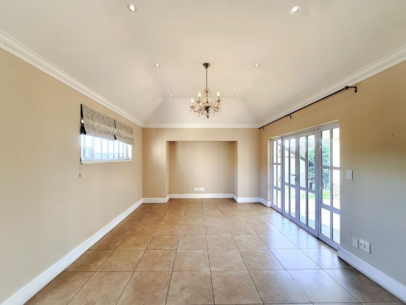 Spacious living area featuring vaulted ceilings, tiled flooring, and large glass sliding doors providing ample natural light and access to the outdoors.