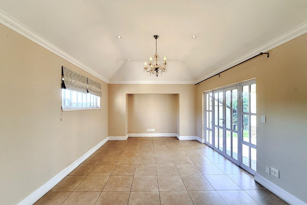 Spacious living area featuring vaulted ceilings, tiled flooring, and large glass sliding doors providing ample natural light and access to the outdoors.