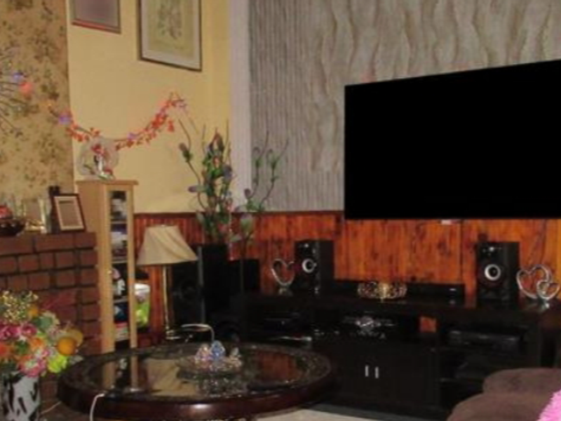 A living room featuring a brick fireplace and wood paneling, providing a traditional aesthetic.