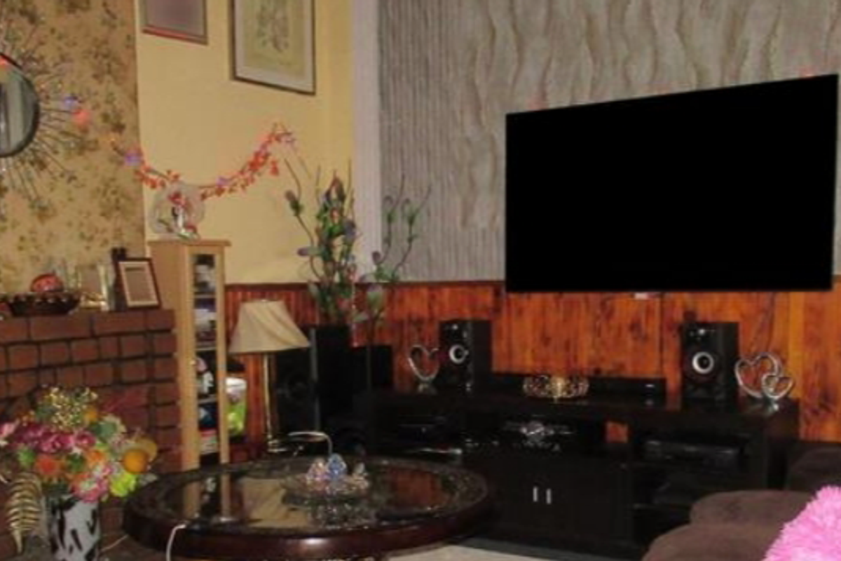 A living room featuring a brick fireplace and wood paneling, providing a traditional aesthetic.