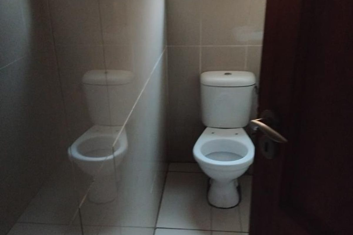 A compact, tiled bathroom featuring a standard white toilet and a frosted glass window for privacy.
