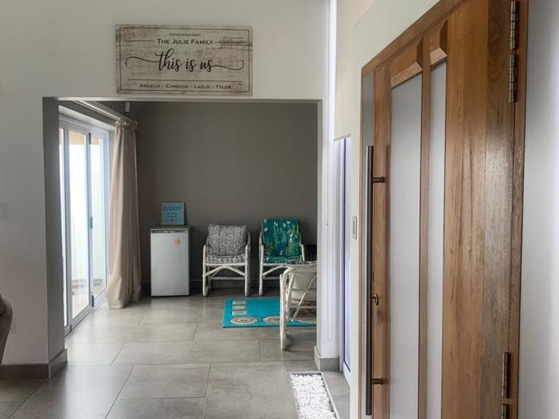 A bright living area featuring large format floor tiles, modern timber-framed glass doors, and a decorative stone inlay detail leading to an outdoor space.