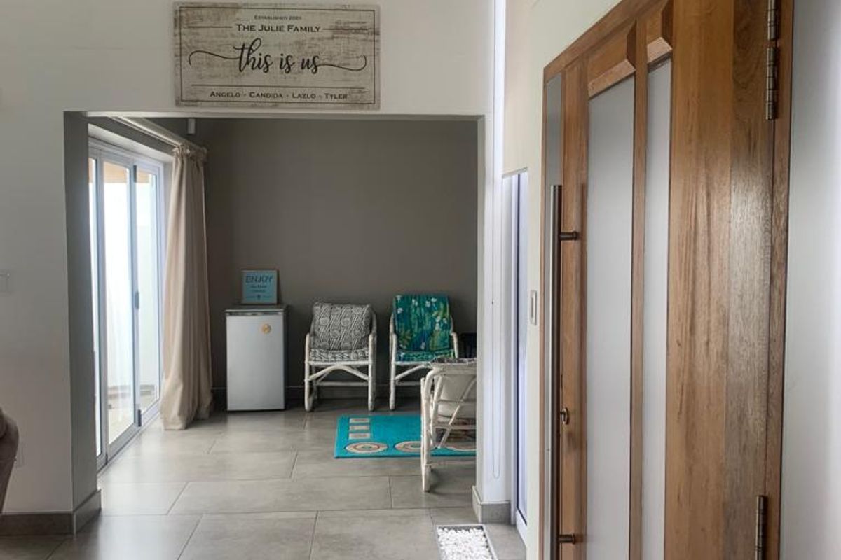 A bright living area featuring large format floor tiles, modern timber-framed glass doors, and a decorative stone inlay detail leading to an outdoor space.