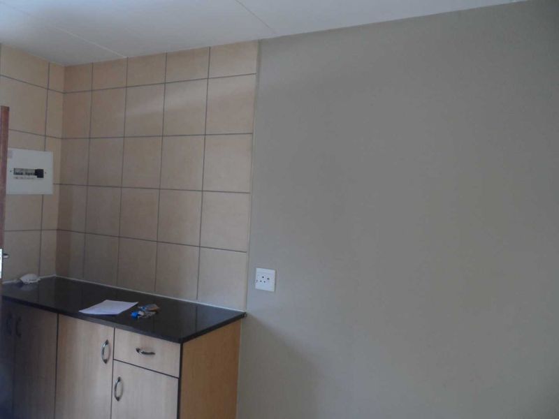 A compact kitchen area featuring built-in cabinetry, a dark stone countertop, and a tiled splashback, providing a functional foundation for a modern kitchen space.