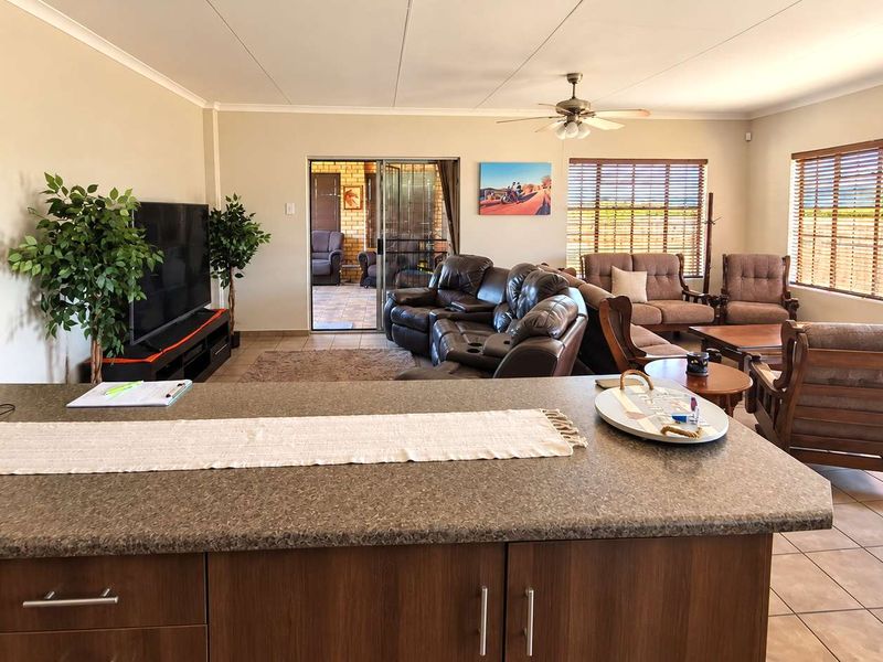 Spacious open-plan living area featuring a kitchen island, tiled flooring, and large sliding doors leading to an outdoor patio space.