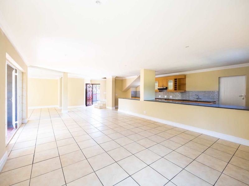 Spacious open-plan living area featuring tiled floors, recessed lighting, and a functional kitchen with granite countertops and ample cabinetry.