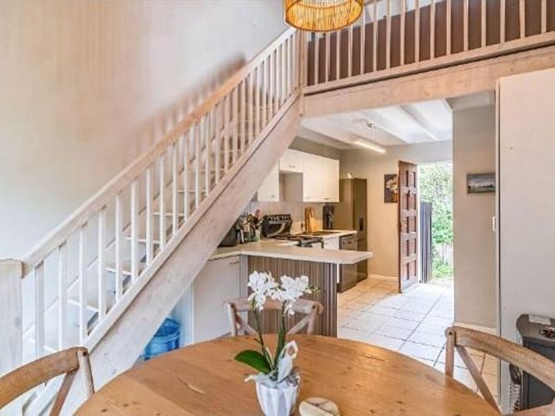 Open plan living area featuring a staircase leading to a mezzanine level, adjacent kitchen with tiled flooring, and direct access to the exterior.