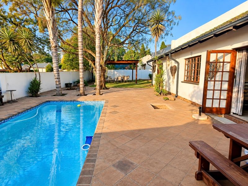 Outdoor pool area featuring a tiled patio, swimming pool, and a rear garden with a pergola, providing a functional space for outdoor relaxation.