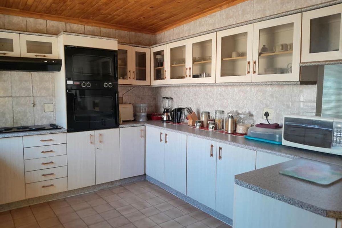 A functional kitchen featuring built-in cabinetry, integrated double oven, extractor fan, and tiled flooring with a timber-paneled ceiling.