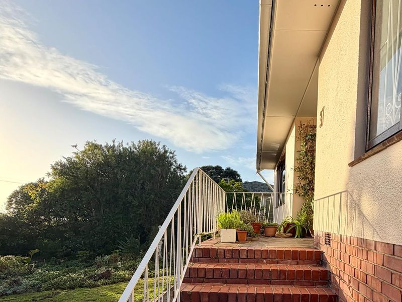 Front entrance featuring a brick staircase with a white metal balustrade, leading to a stucco-finished facade with brick detailing.