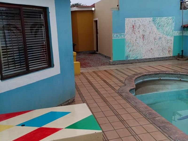 Outdoor pool area featuring a tiled patio, built-in bench, and exterior walls with decorative murals.
