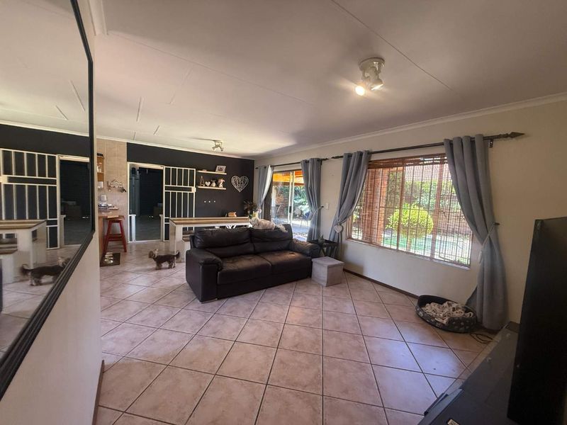 Spacious open-plan living area featuring tiled flooring, large windows for natural light, and direct access to the outdoor patio through sliding glass doors.
