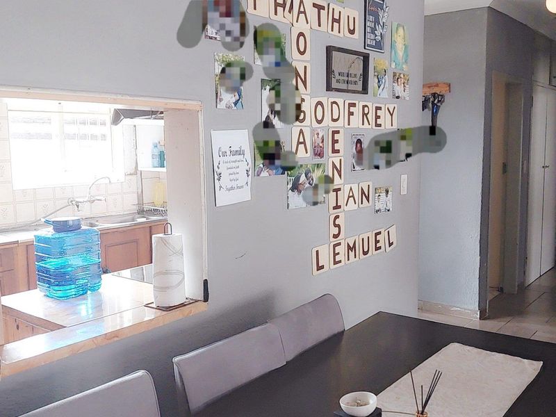 Open plan dining area featuring a serving hatch looking into the kitchen, with tiled flooring and neutral wall finishes.