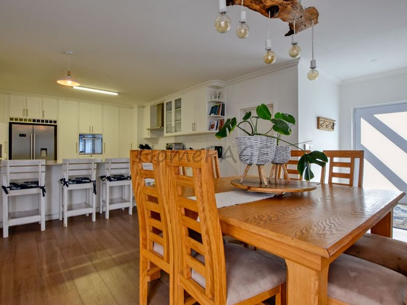 Spacious open-plan kitchen and dining area featuring modern white cabinetry, a functional kitchen island, and warm laminate flooring throughout.