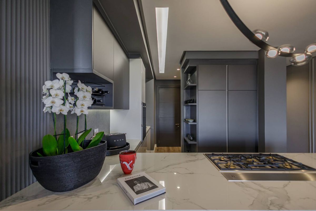 Modern kitchen featuring sleek dark cabinetry, a marble-look island countertop, and a built-in gas hob, offering a sophisticated and contemporary culinary space.