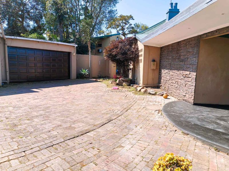 Front exterior view of the townhouse featuring a paved driveway, garage access, and decorative stone cladding on the building facade.
