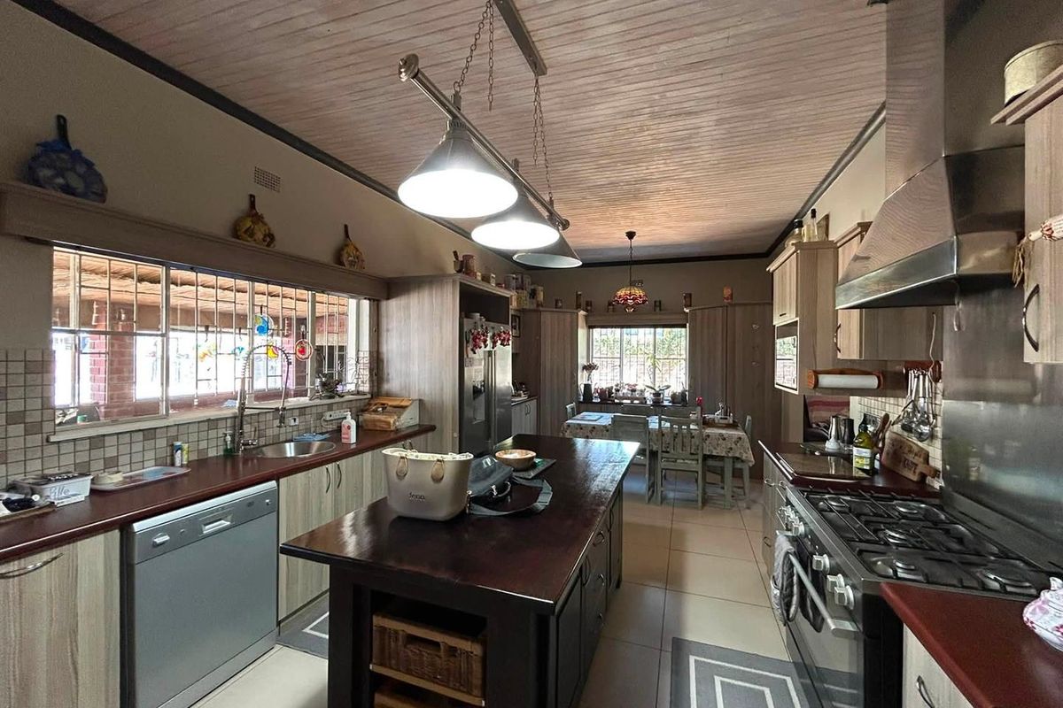 Spacious kitchen featuring a central island, gas stove with extractor, timber ceiling, and ample built-in cabinetry with a tiled splashback.