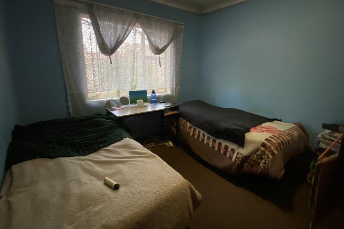 A bedroom featuring blue walls and a window with curtains, providing a functional space for rest.