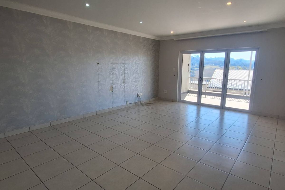 Spacious, light-filled living area featuring tiled flooring, recessed lighting, and sliding glass doors leading to a balcony with scenic views.