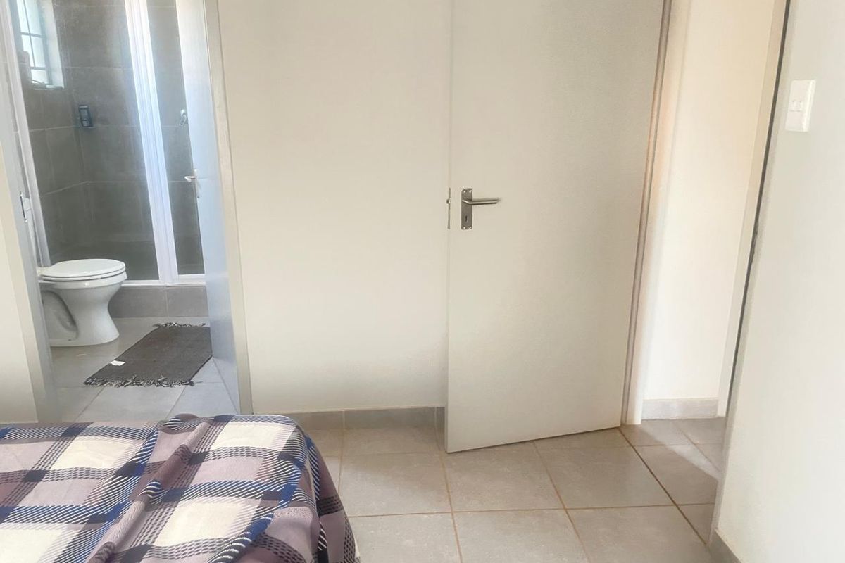 A bedroom featuring tiled flooring and an attached en-suite bathroom with a shower and toilet.