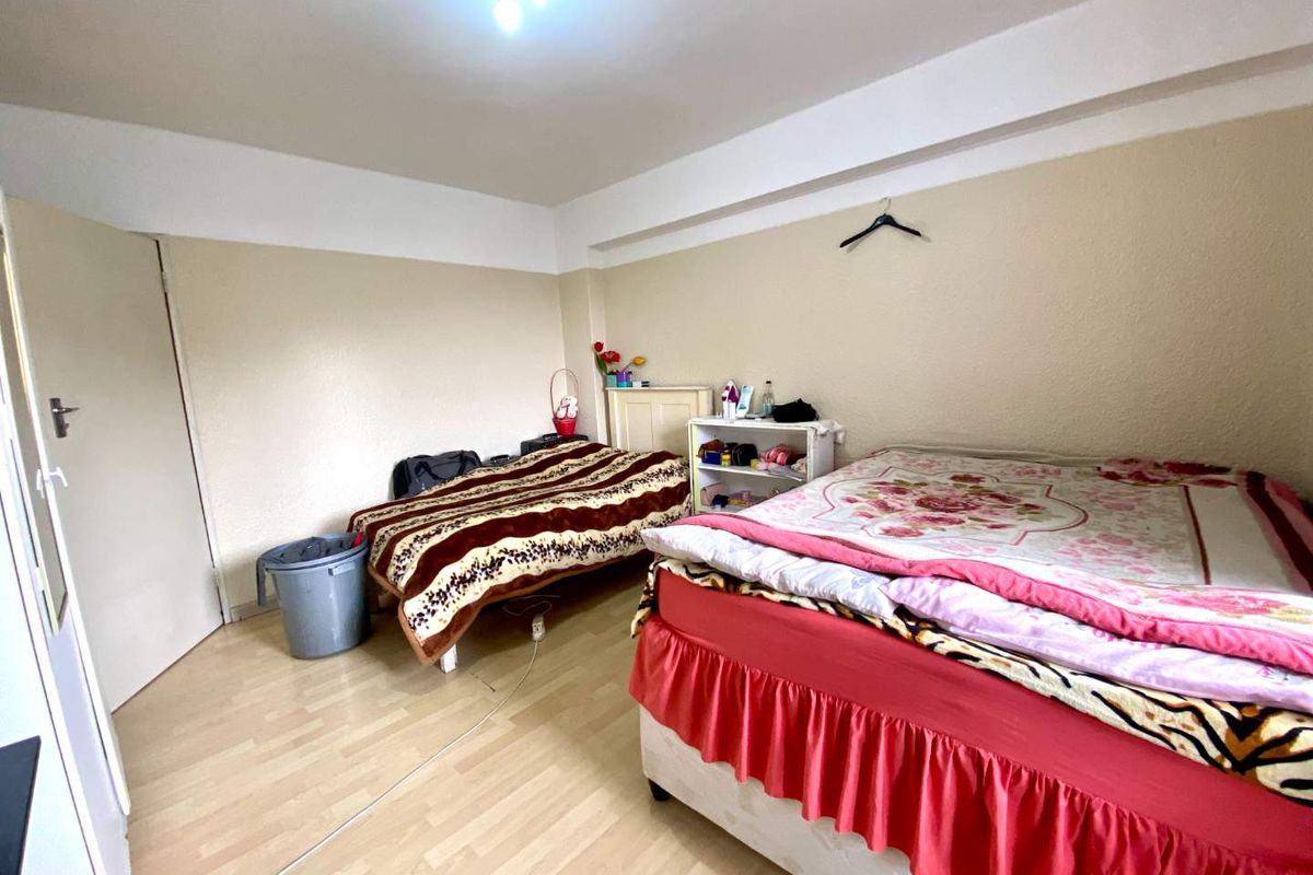 A bedroom featuring laminate flooring and a central ceiling light fixture, providing a functional space for sleeping arrangements.