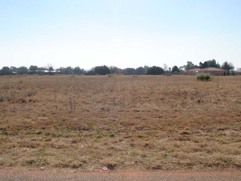 A wide-angle view of a vacant residential plot featuring open grassland, suitable for future development.