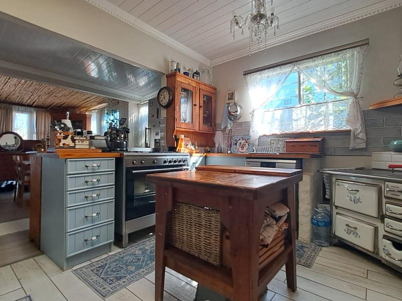 A rustic-style kitchen featuring timber cabinetry, wooden countertops, a freestanding oven, and a tiled backsplash, offering a warm and traditional aesthetic.